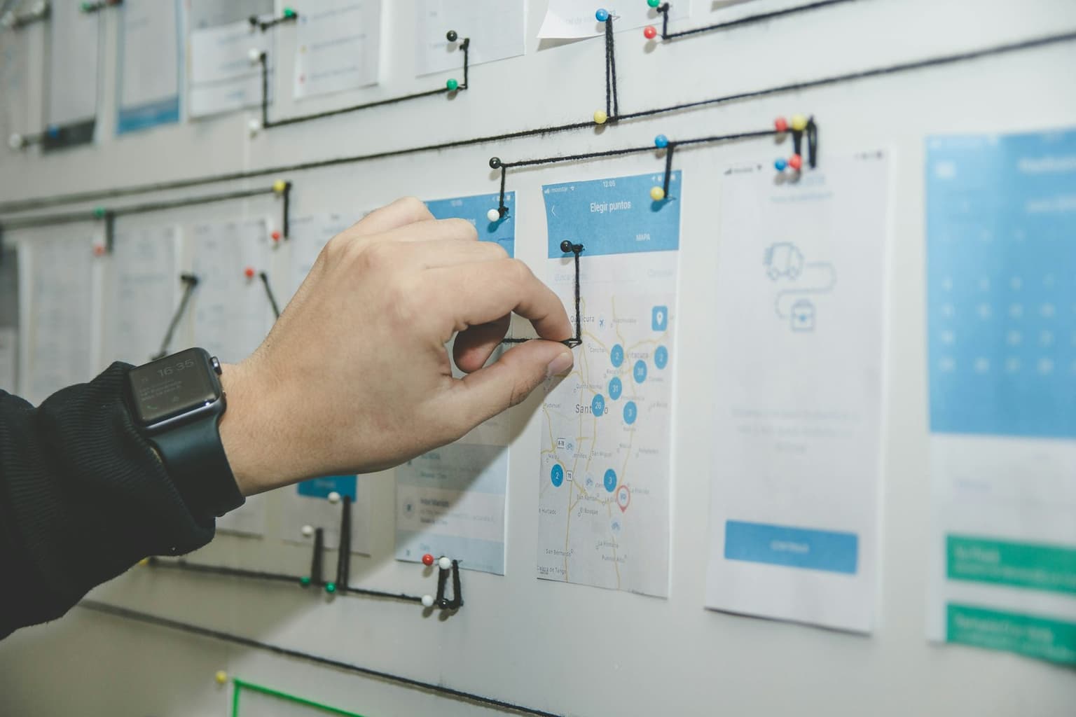 A person arranging interface screens on a planning board