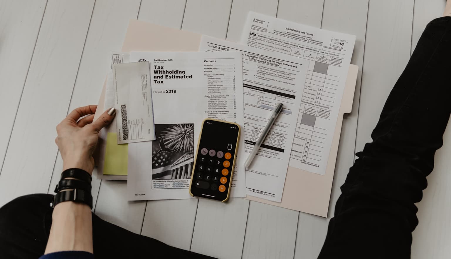A person reviewing invoices and costs with a calculator