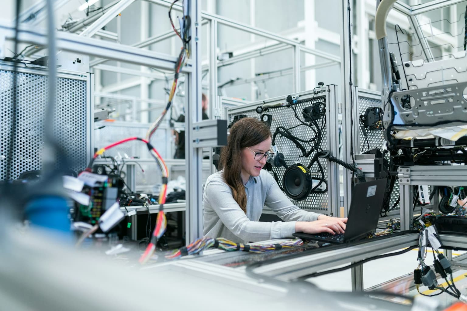 An engineer working from a laptop beside a manufacturing line